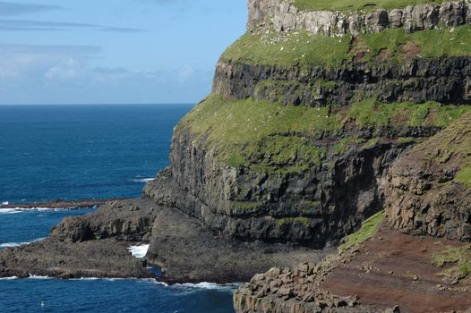 Faroese steep green cliffs and clear blue ocean, Gasadalur, Vagar.