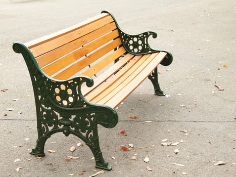 An orange bench in the park on asphalt