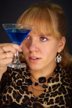 A young woman looks at a glass with an unusual cocktail