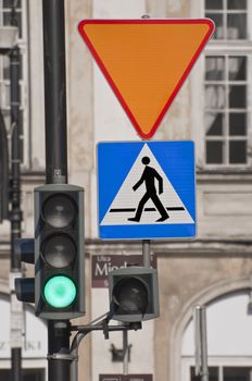 Green traffic light and pedestrian crossing sign.
