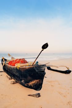 Old boat with fishing net on sandy shore. In Goa