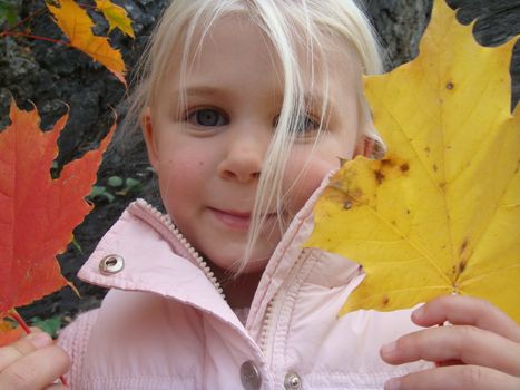 girl holding red and yellow leaves