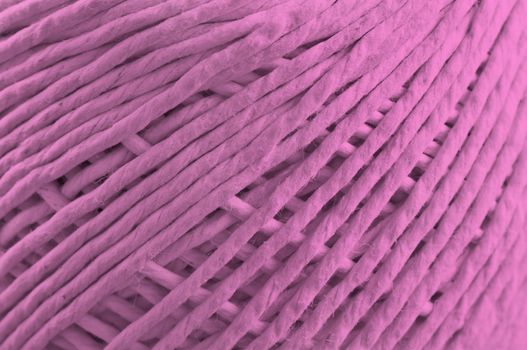 Close up on the fibres of a ball of string with pink light effect filter