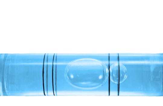 Close up on a the bubble of a blue spirit level arranged over white