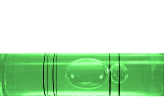 Close up on a the bubble of a green spirit level arranged over white