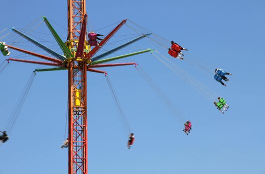 Colored carousel in an amusement park against  blue sky