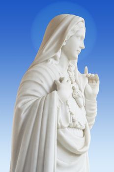 beatiful white statue of Virgin Mary on blue background