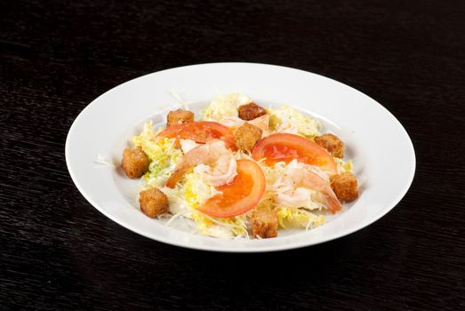 Salad of tiger shrimps, lettuce, chinese cabbage, tomato, garlic rusk, parmesan cheese and sauce