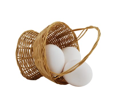 three white eggs spilled from straw interwoven basket isolated on white background