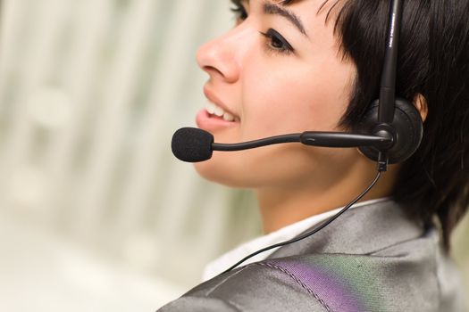 Profile of an Attractive Young Mixed Race Woman Smiles Wearing Headset In An Office Setting.