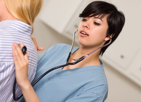 Attractive Mixed Race Young Female Doctor Using Stethoscope to Listen to Patient's Vital Signs.