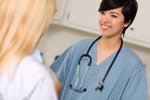 Attractive Mixed Race Young Female Doctor Talking with Patient in an Office Setting.