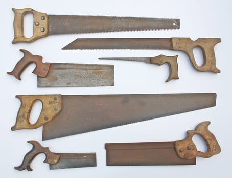 A collection of several rusty handsaws, some of them are still in use.