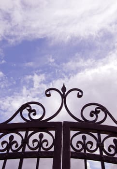 Sky view through old decorated metal gates. Architectural solution made ??of steel.