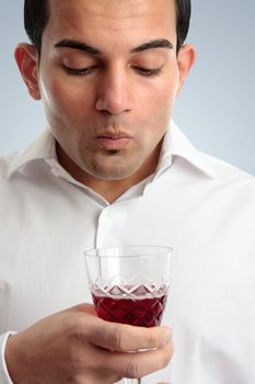 A male wine taster savours a wine by swirling and holding it in the mouth for a few seconds to saturate the taste buds.  White background.