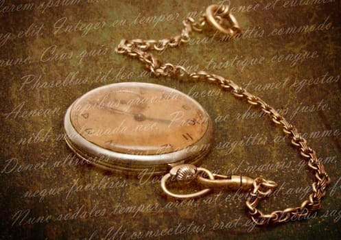 Time concept - vintage pocket watch with chain lying on rough green  surface - shallow depth of field