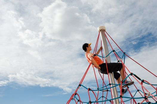 Teenager climbing on top of a jungle gym rope 