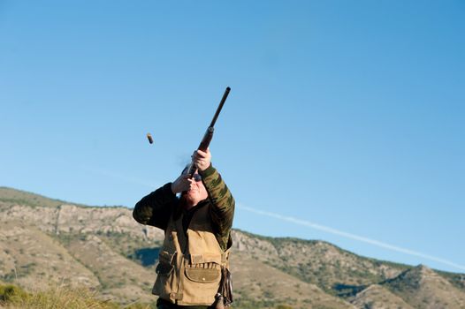 Hunter in action aiming and shooting his rifle