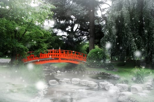 Red bridge under snow in a japanese garden