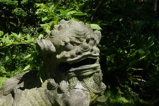 Stone statue of a lion in japanese garden