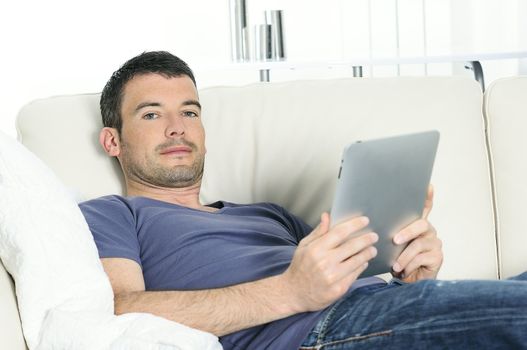 attractive relaxed and positive man is surfing on his tablet