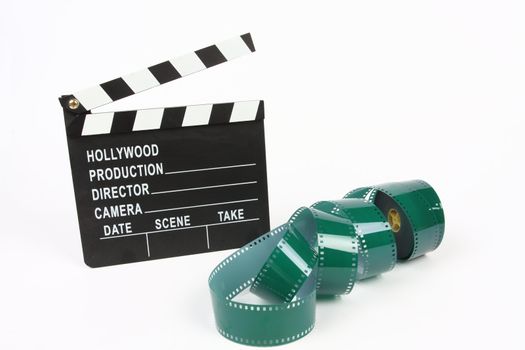 Movie clapper board and film roll over white 