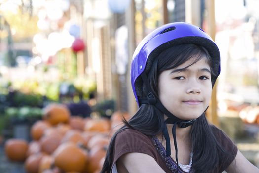 Little girl with purple bike helmet on bicycle