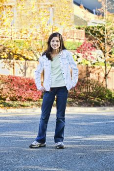 Smiling biracial eleven year old girl standing in middle of street