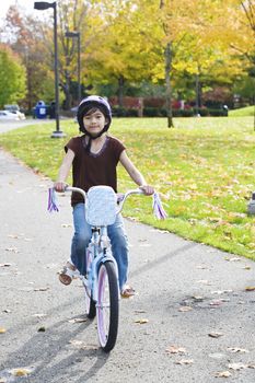 Little girl riding bike in park in late summer, early autumn