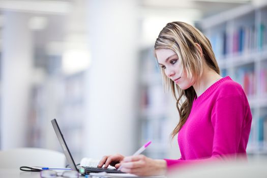 in the library - pretty, female student with laptop and books working in a high school library (color toned image)