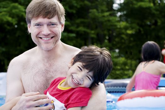 Father holding disabled son in pool