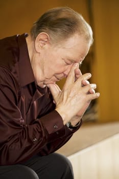 Elderly man praying in dark church