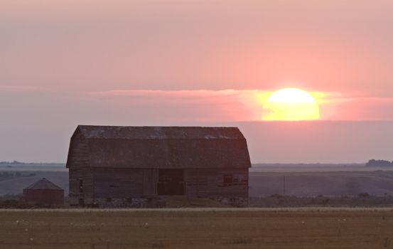 Sun nearing sunset behind old barn