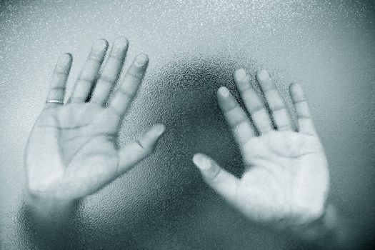 Man's hands on a background of a wet glass.