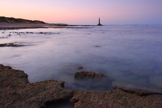 Rocks and sea with a warning beacon in the background