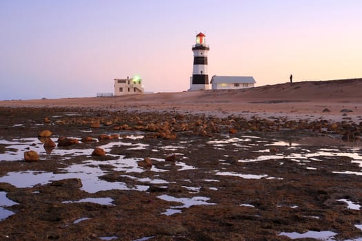 Lighthouse and sunset at the coast at low tide