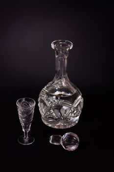 Crystal vodka decanter and glass on a black background