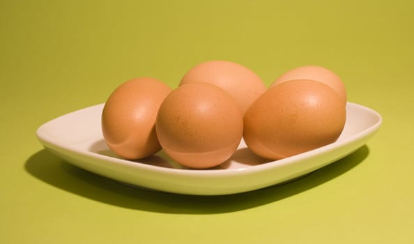 Eggs on fresh green background (on the white plate)