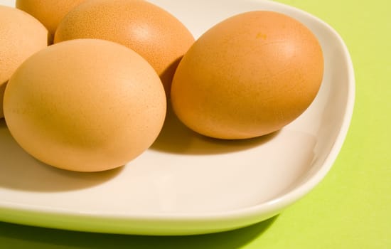 Eggs on fresh green background (on the white plate)