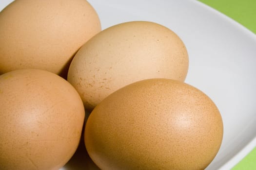 Eggs on fresh green background (on the white plate)
