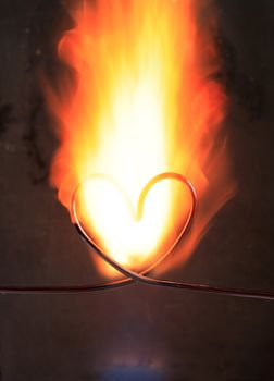 Heart made from wire in fire on dark background