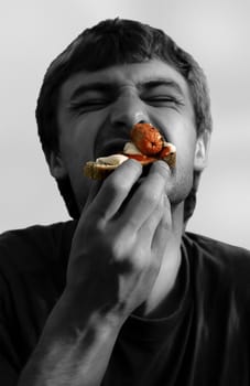a young hungry man biting a very tasty sandwich