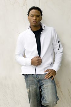 Attractive young man in a stylish jacket and jeans on against the wall.