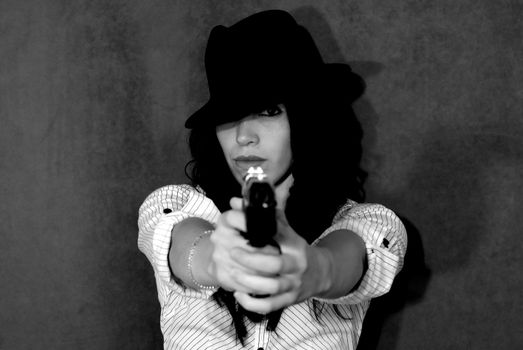 Gorgeous female model posing with a gun in a studio.