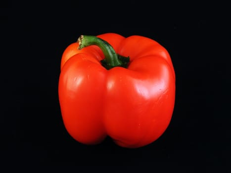 A red bell pepper against a black background.