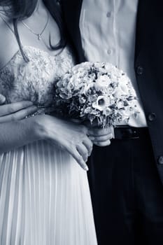 Bouquet of flowers on a background of a dress of the bride and a suit the groom.