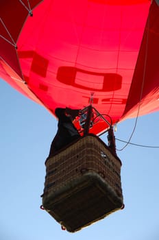 A man is standing in his hot air balloon waving with his hand.