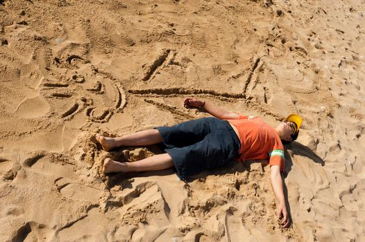 Creative teenager sunbathing next to his cartoon