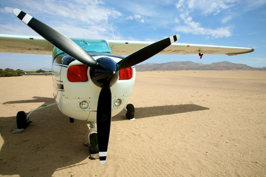 Small airplane in the desert of namibia with a blue sky and the sert all around