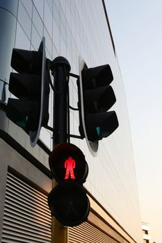 Traffic control lights with red for pedestrian crossing against modern building